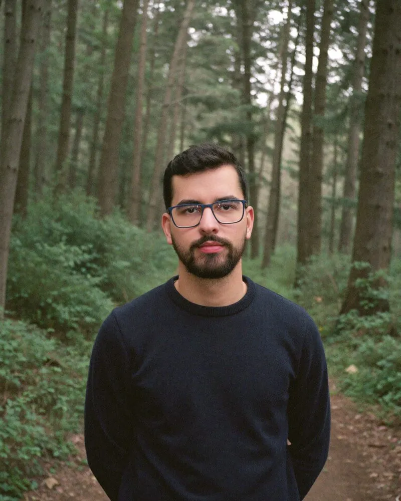 Emerson, de suéter escuro, numa trilha no meio de um bosque